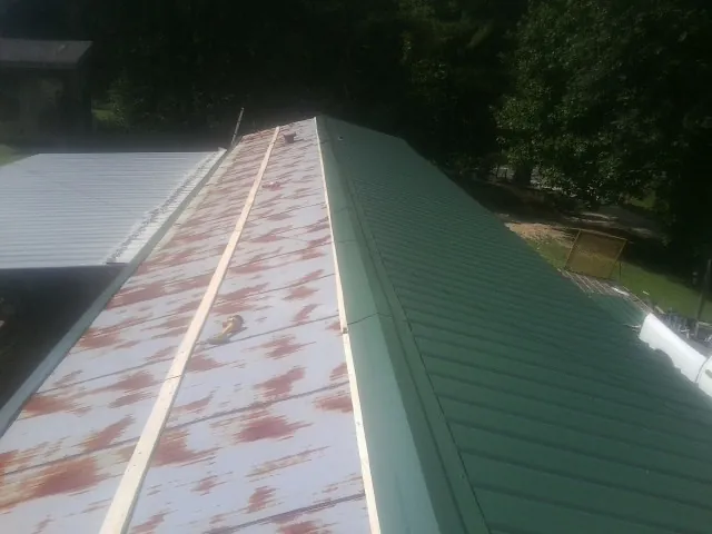 Old rusted panels beside newly installed green metal roofing — Wind Damage Roof Repair by Roofing Brothers in Merion Station