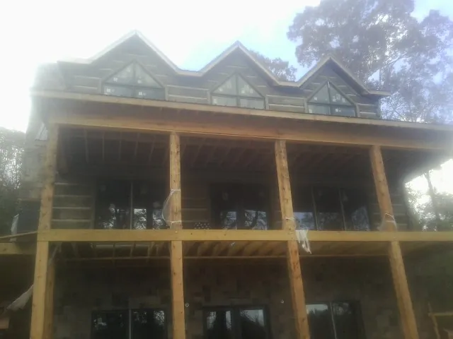 Dormers and porch framing on a large log home under construction — Roof Coating work by our crew in Merion Station