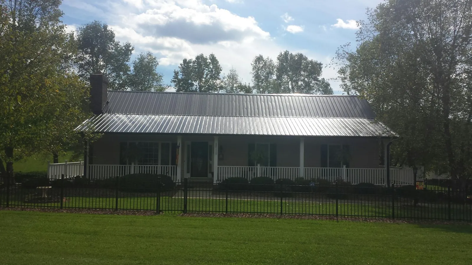 Gray metal roof on a brick ranch with a full width front porch — Gutter Guard Installation work by our crew in Merion Station