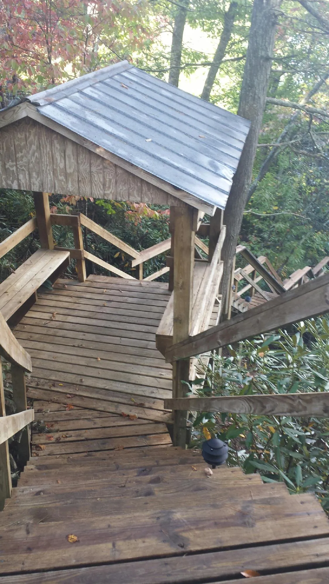 Metal roofed shelter over wooden steps on a wooded walkway — Skylight Repair & Installation work by our crew in Merion Station