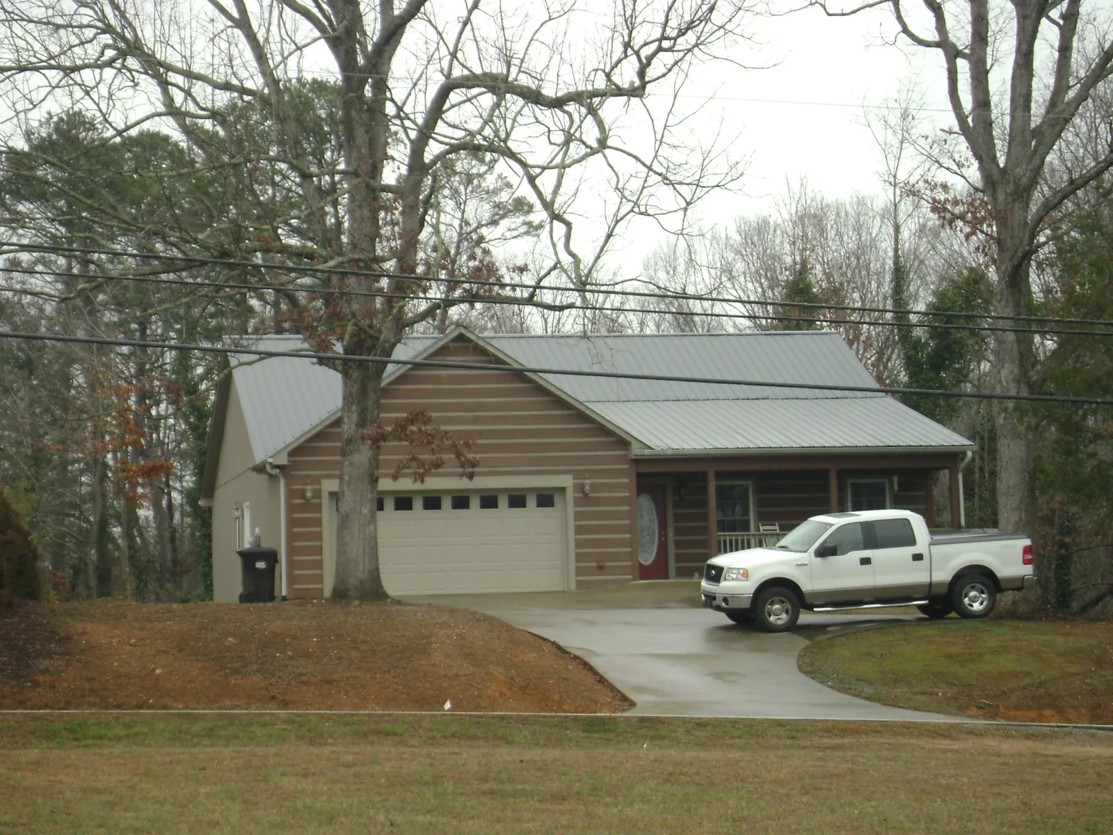 Gray metal roof on a log sided house with an attached two car garage in Merion Station