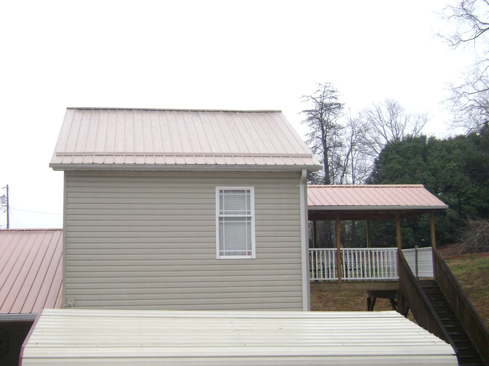 Tan metal roofs on a two story addition and attached porch, from a Roof Replacement job in Merion Station