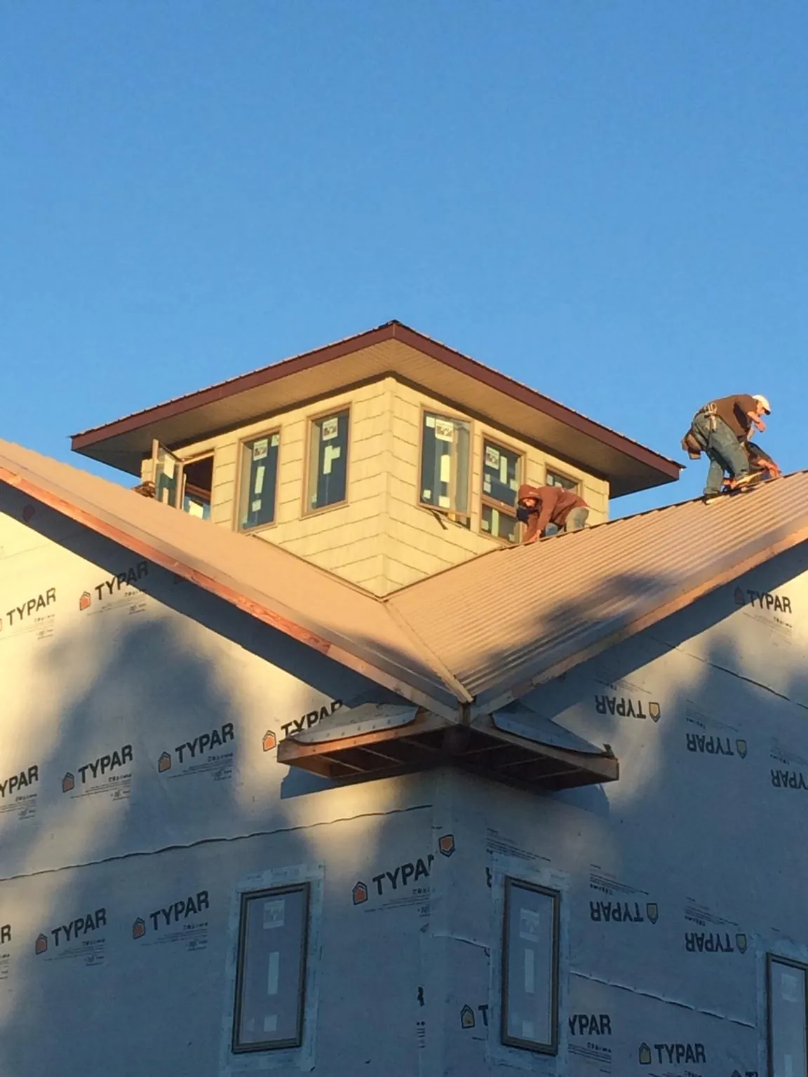 Roofers working around a rooftop cupola on a new metal roof at sunset — Roof Waterproofing in Merion Station by Roofing Brothers